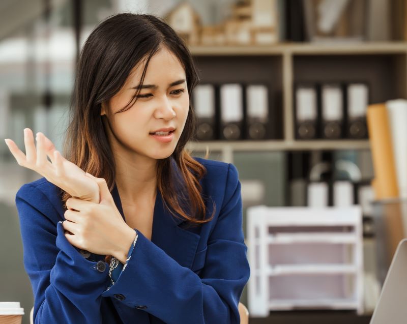 A female office worker rubs her sore wrist.