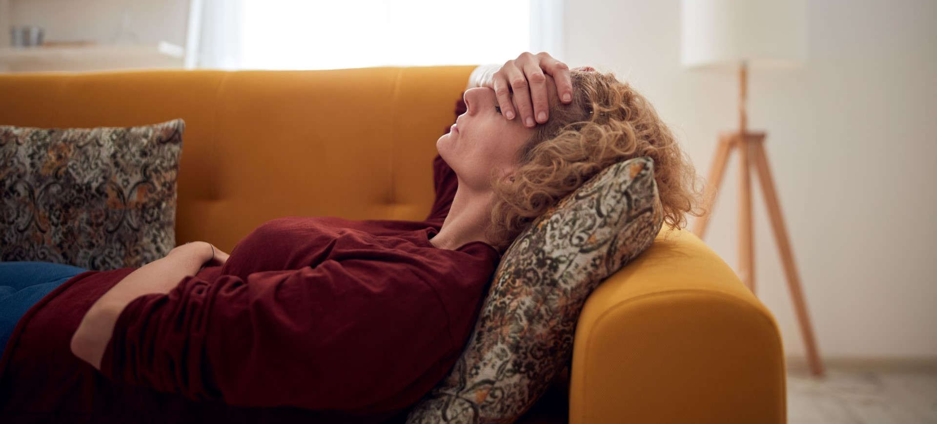 Woman lies on a couch with a sore head.