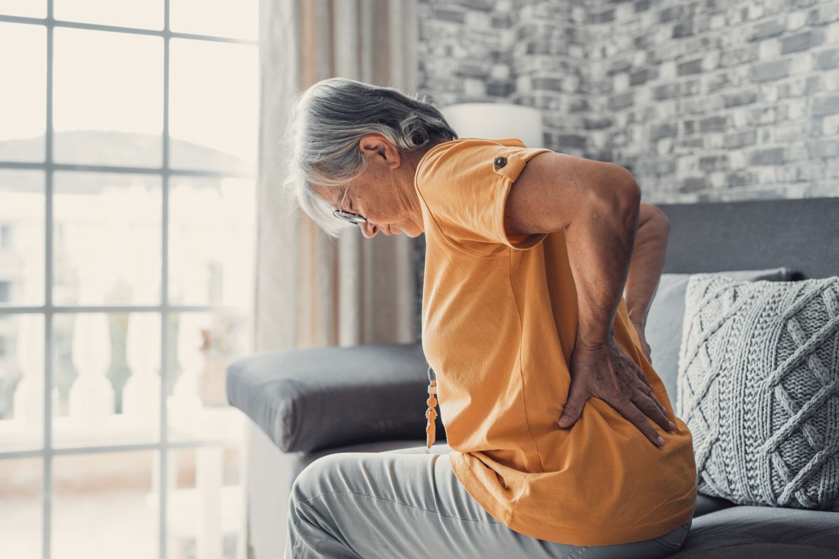 Elderly woman holds her sore back.