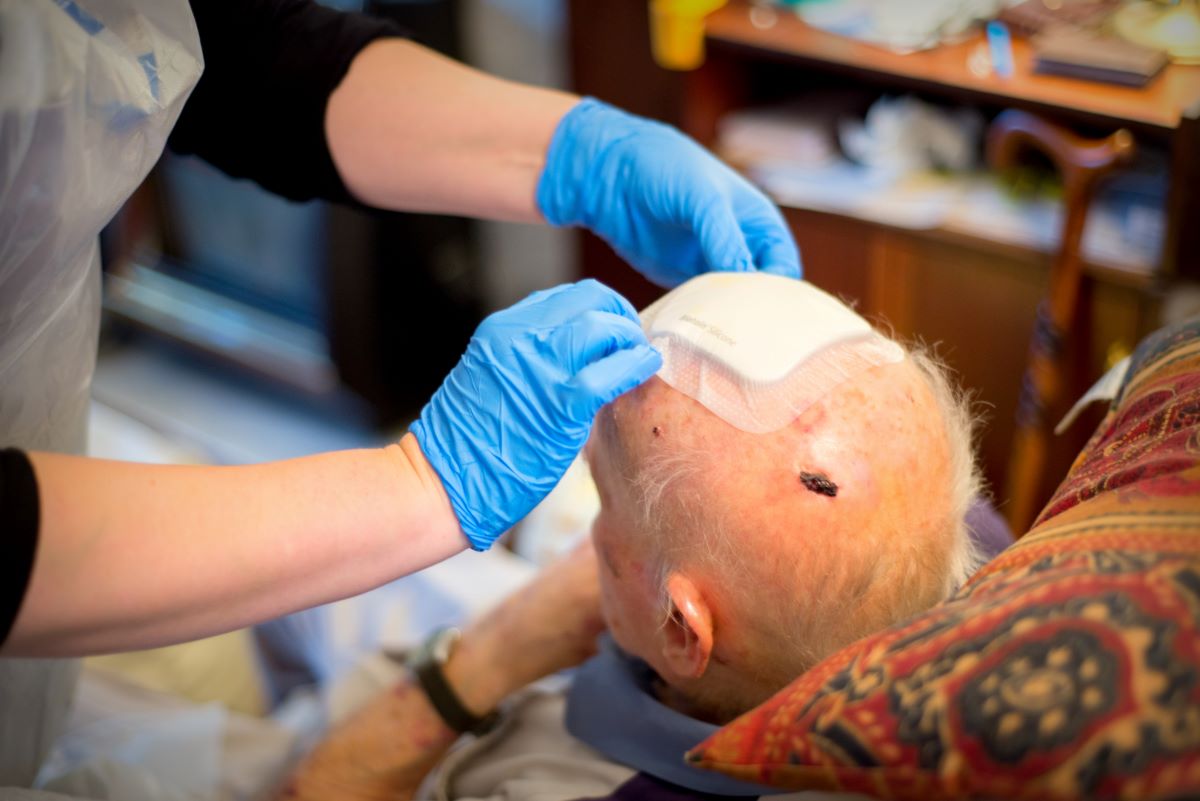 Nurse changes a dressing on a man's injured head.