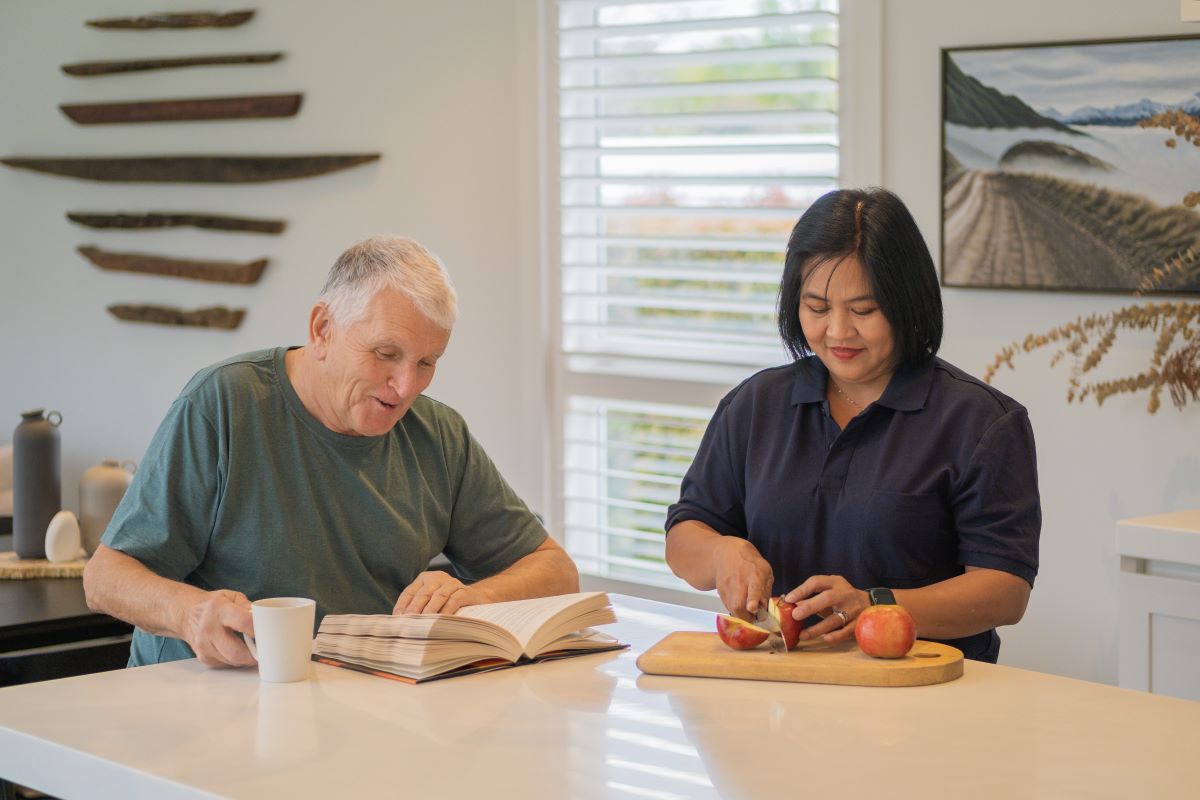 A carer prepares food for an elderly man.