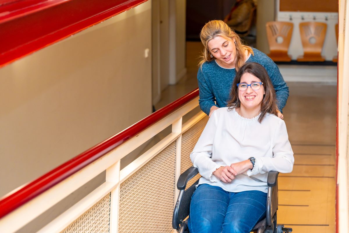 A carer helps a woman in a wheelchair